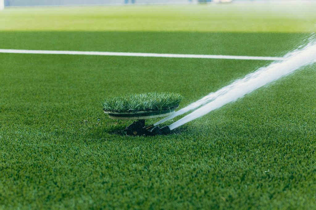 An active sprinkler watering a vibrant green sports field, enhancing the lush grass surface.